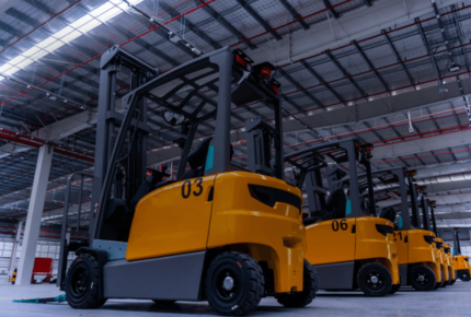 Reihe von gelben Gabelstaplern in einer Lagerhalle, mit sichtbaren Nummern auf den Fahrzeugen.